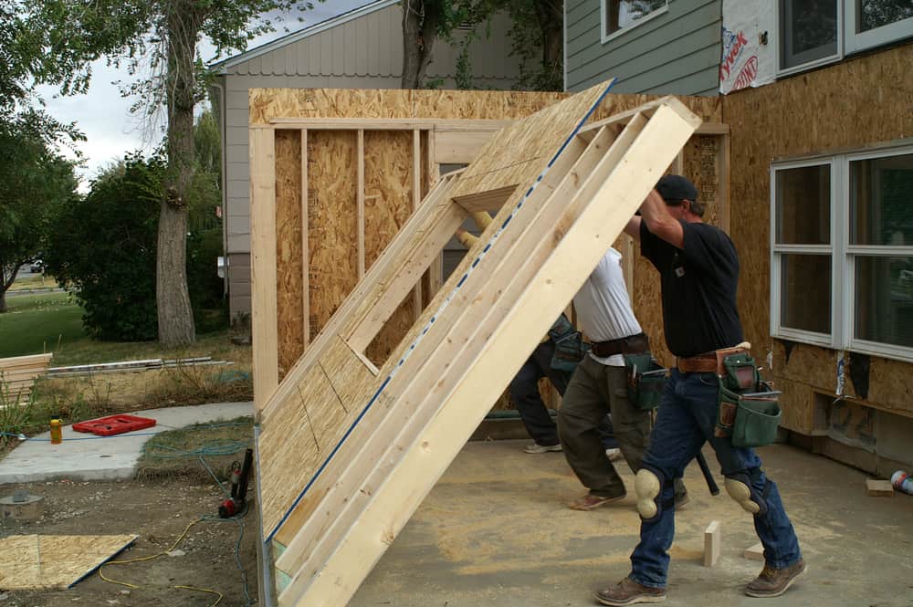 men lifting wall for home addition.