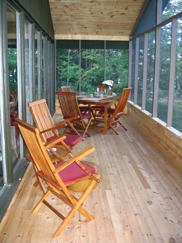 narrow screened in porch with chairs.